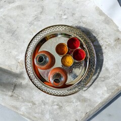 Top view of Indian puja thali with kumkum, turmeric, rice and diya on decorative metal plate, used in Hindu rituals and festivals.