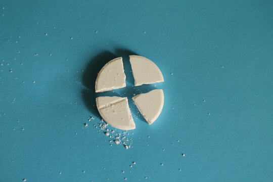 a closeup shot of a white pill on a blue surface
