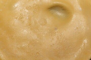 A close up view of a golden brown surface with small bubbles and a slight indentation texture