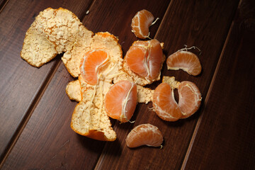 Fototapeta premium Fresh citrus segments and peels scattered on a wooden surface