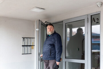 Middle aged man standing at apartment building entrance on rainy day, urban residential lifestyle and everyday city routine
