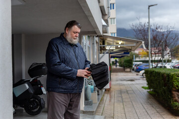 Man walking out of residential building with umbrella on rainy day, everyday urban life and weather concept