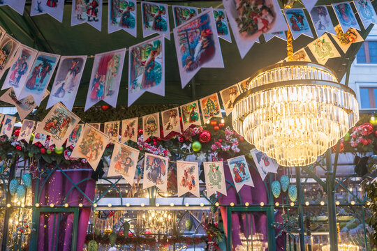 Moscow, Russia - 30 December 2025: Festive pavilion ceiling with hanging garlands of vintage Christmas postcards and large crystal chandelier,