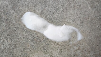 Snowy shoe print on concrete surface. A white snow resembling a footprint contrasts against a rough concrete surface. The texture of the concrete adds depth and interest to the composition.
