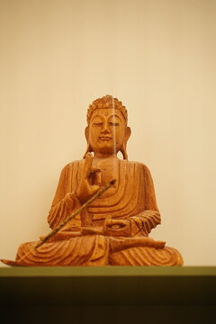Estatua de Buda de madera tallada con incienso encendido. Concepto de meditaci&oacute;n y paz interior.