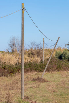 One of the wooden poles of an old power line was dangerously tilted by bad weather in the countryside, Fauglia, Pisa, Italy