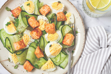 Delicious salmon and egg salad served on a plate with fresh cucumber and herbs for a healthy meal at lunchtime