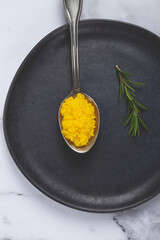 pearl yuzu, yuzu caviar - pearl, on a spoon, top view, on a dark gray plate, there are no people.