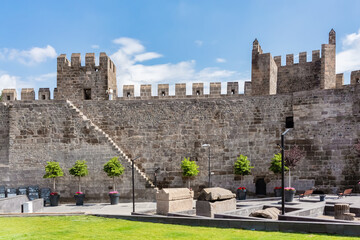 Fototapeta premium Medieval fortress walls and towers of Kayseri citadel with stone artifacts and green garden area, historical site in Turkey