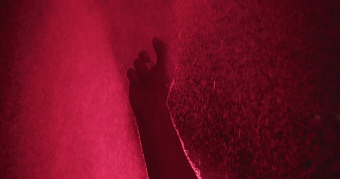 silhouette of hand in red light in super slow motion reaches upward