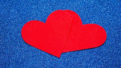 Obraz premium Two Red Heart Shapes on a Blue Glitter Background in a Simple Design