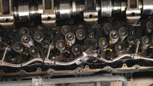 The camshaft and valve train components of a car engine. Mechanics inspect and document metal engine components. An engine mechanism on a work bench in a workshop during professional auto repair.