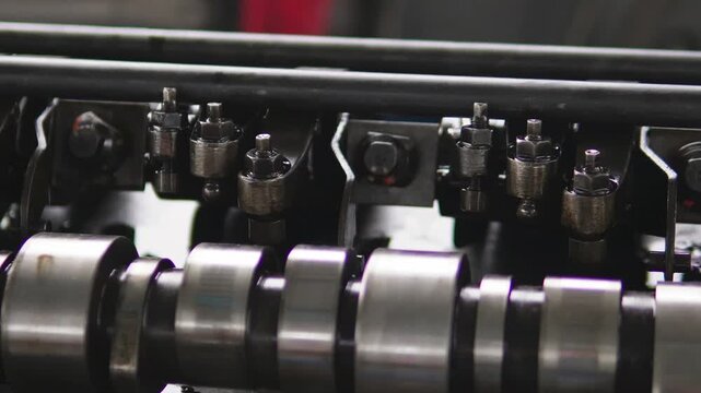 The camshaft and valve train components of a car engine. Mechanics inspect and document metal engine components. An engine mechanism on a work bench in a workshop during professional auto repair.