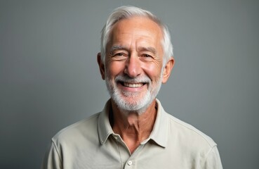 Obraz premium Closeup portrait of smiling senior man with grey hair and beard. Elderly grandfather looking friendly at camera. Mature caucasian male in light shirt.