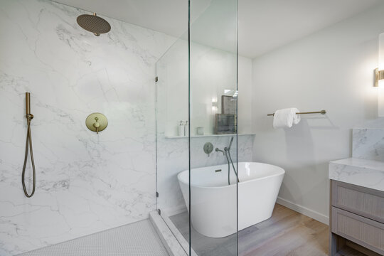 Bright modern bathroom primary powder room sink glass wall shower free standing bath tub white marble granite houseplant rectangle round mirror towel bathrobe clean contemporary