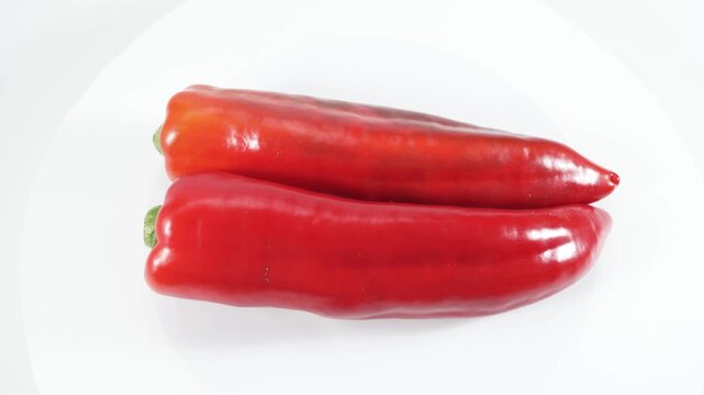 Two red chili peppers rotate vertically in a minimalist studio setting. A clean food video showcasing the concepts of heat, spice, and ingredients.