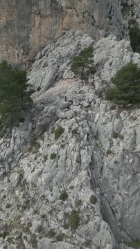 Monta&ntilde;ero en una pared abrupta saludando a un dron que se aleja , video vertical para redes sociales