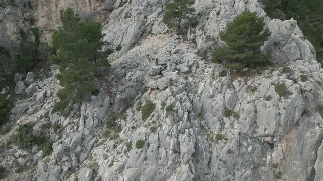 Monta&ntilde;ero en una pared abrupta saludando a un dron que se aleja , video horizontal