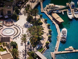 Aerial drone view of Dubai Marina harbor with many luxury yachts, capturing modern waterfront and city skyline. Floating boats on canal
