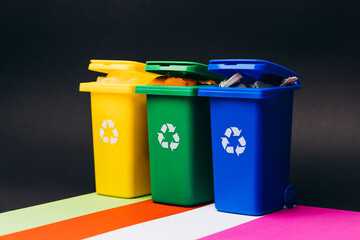 Colorful recycling bins in vibrant hues of yellow, green, and blue arranged on a bright surface, promoting eco-friendly waste management practices