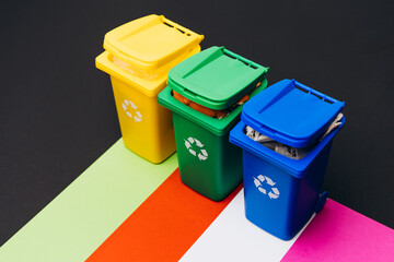 Colorful recycling bins arranged on vibrant paper background, promoting environmental awareness and sustainable waste management practices for eco-friendly living