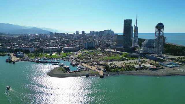 Bird's-eye view of Batumi landmarks in clear winter. 4K horizontal drone footage captures the city's architecture, iconic buildings, and streets under sunny skies during a warm snowless winter.