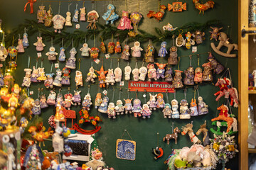 Moscow, Russia - 30 December 2025: Display of handmade cotton Christmas toys and figurines hanging on green wall in festive shop,