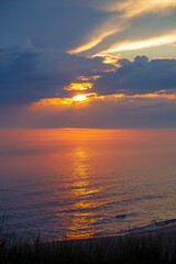 Sun Peeking Through the Clouds on a Calm Lake at Sunset