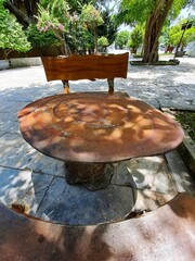 Outdoor furniture designed to look like tree trunks and cross-sections sits on a stone patio surrounded by tropical greenery