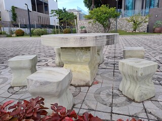 Round white marble garden table with stone stools in outdoor patio