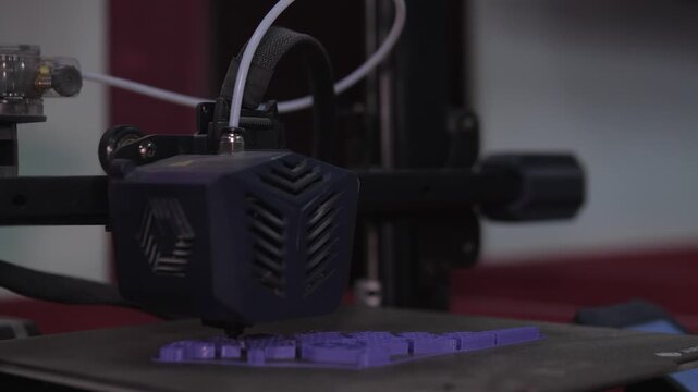 CloseUp D Printer Extruder Aligning Above Purple Test Print On Heated Bed Makerspace Environment, Tubing And Gantry Visible, Focus On Setup, Adjustment And Nozzle Path