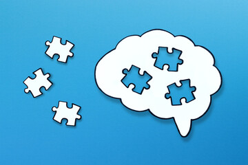 Missing puzzle pieces completing a brain symbol on blue background. Mental health and problems with memory.
