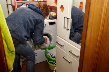 Woman opens a washing machine to put dirty clothes in. Woman using washing machine at home
