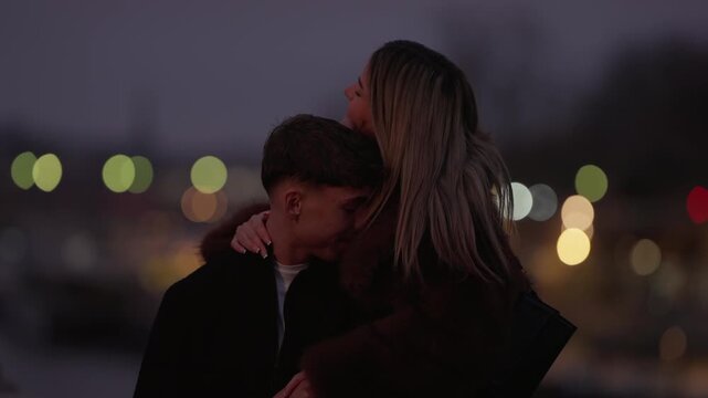 A loving couple embraces in Paris at night The woman kisses the man's forehead in a tender moment Bokeh lights create a romantic atmosphere in the cityscape background.