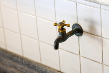 closeup of old style brass water tap installed in public rest room.