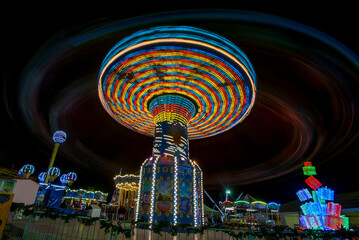Colorful swing carnival ride at night creating light trails