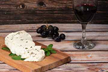 Slices of cyprus halloumi cheese red wine and grapes on wooden board