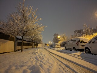 Winter night in the city with snow-covered cars, sidewalks and roads. Snow disaster in a housing estate in Eastern Europe.