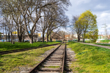 Old abandoned railway tracks in the city in spring. Disused railway track in Brno.