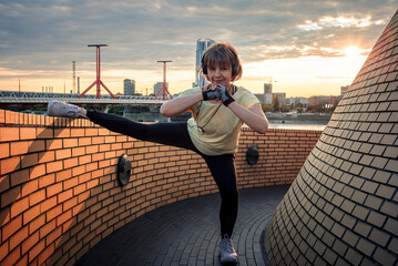 Young woman stretches on the roof looking at camera