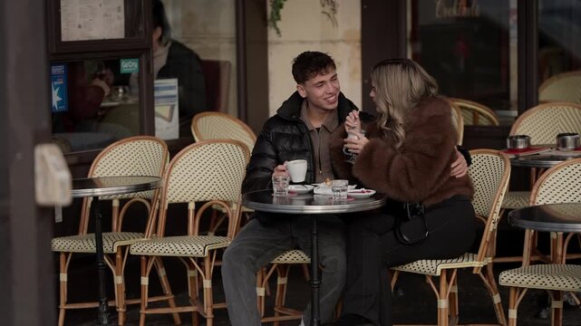 A young couple shares a dessert at an outdoor in Paris France The lovers are seated at a table embracing and enjoying a sweet intimate moment together during daytime.