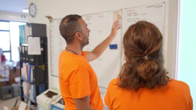 Team of employees reviewing schedules and work assignments on the task board