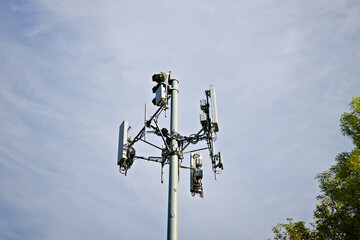 Cell tower with mounted wireless antennas and communication equipment against a clear sky in Corona, California.