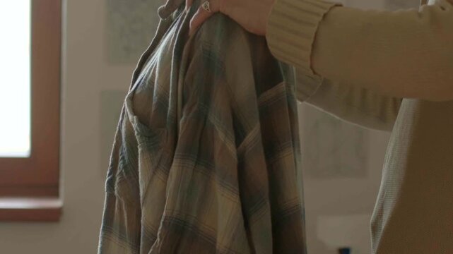 Cleaning and smoothing fabric at window, Closeup of hands smoothing fabric in domestic setting morning, Carefully adjusting and smoothing white shirt in cozy home environment