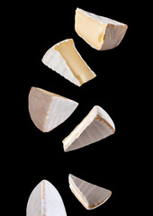 pieces of camembert cheese falling on dark background