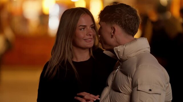A romantic couple in Paris at night The man kisses the woman on the cheek in a tender moment Warm bokeh lights create a romantic atmosphere Handheld shot capturing an intimate moment of love and affec