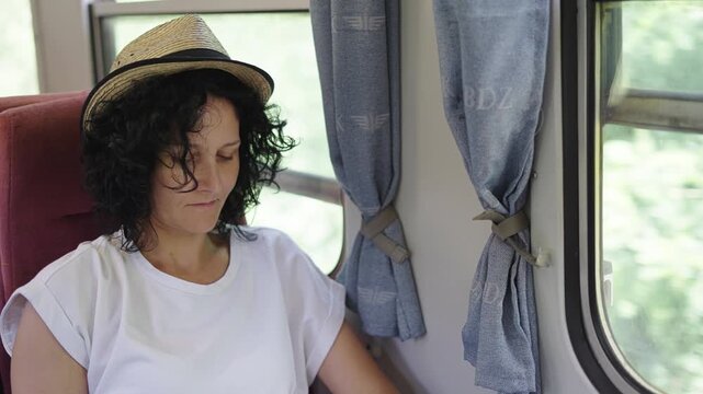 Woman traveler with hat surf online on smartphone during her daily commute on vintage train