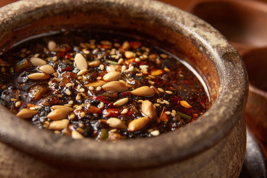 A close-up of Pepi�n, a rich, dark traditional stew with roasted seeds and vegetables, served in a rustic ceramic bowl.