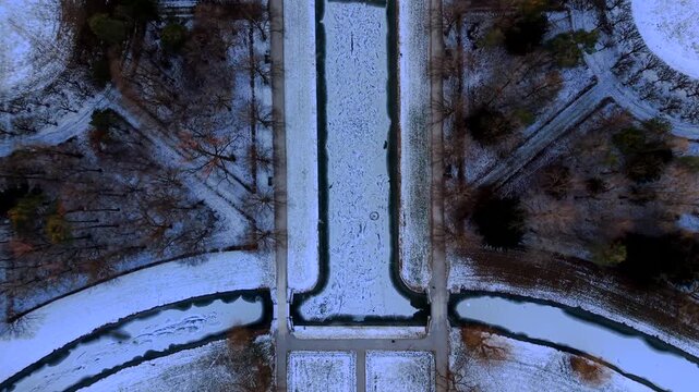 Drone panorama of Schleissheim Palace in Oberschleissheim, Bavaria, Germany. Winter scenery with snow covered gardens and baroque palaces glowing in dramatic orange sunset sky.