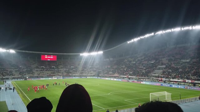 Football, soccer supporter fans in full stadium celebrate a goal in open air roof stadium at night